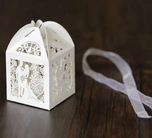Detail of white laser-cut hollow wedding favor box with Mr & Mrs bride and groom design
