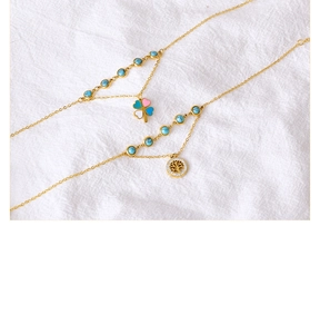 Detail of double-layer gold anklet with turquoise beads and tree of life charm
