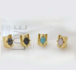 Detail of four gold vintage rings with assorted gemstones on white textured paper
