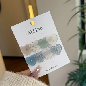 Close-up of heart-shaped hair clips in Morandi colors with floral patterns on a display card