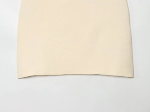 Detail of cream knitted skirt hem showing professional stitching and fine fabric texture