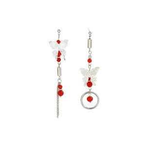 Detail of asymmetric silver butterfly earrings with red bead accents and long tassels
