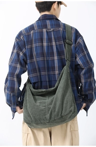 Detail view of the green corduroy crossbody bag texture on a model's back in a white studio