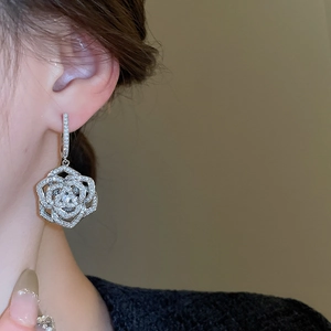 Macro shot of silver camellia earrings with zircon micro-paving and hollow design