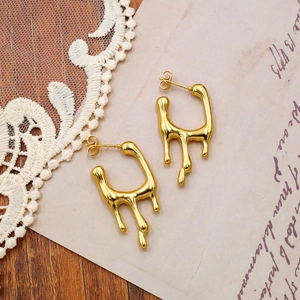 Close-up of golden fluid lava earrings on vintage lace and handwritten paper