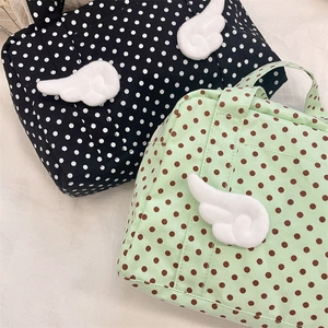 Detailed view of polka dot cosmetic bags featuring 3D plush wing decorations and sturdy handles