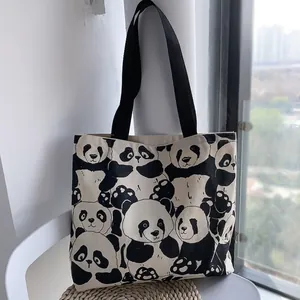 Dettaglio della grande borsa tote in tela con stampa panda e manici neri intrecciati