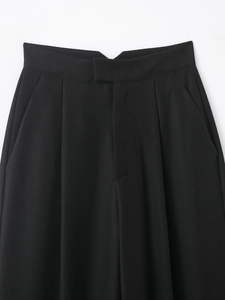 Vue détaillée du pantalon noir à taille haute avec tissu sergé et passants de ceinture
