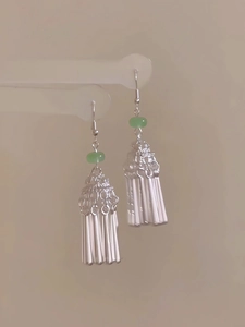 Vue détaillée des boucles d'oreilles à pompons argentés avec perle verte style ethnique