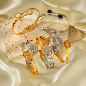 Two-tone stainless steel star bangle set with Roman numerals on a cream satin background