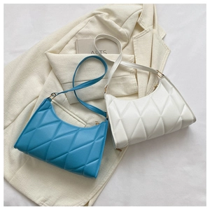 Flat lay of blue and white quilted baguette bags on light-colored suit jackets