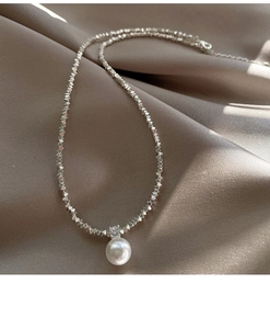 Detailed close-up of a pearl and zircon pendant on a silver-toned faceted chain