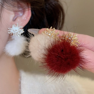 Close-up of winter fur ball earrings with zircon firework studs in three colors
