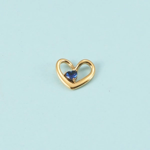Gros plan du pendentif cœur doré avec une petite pierre de naissance bleue en cœur
