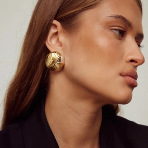 Gros plan de grandes boucles d'oreilles dorées avec texture vintage de style coquillage