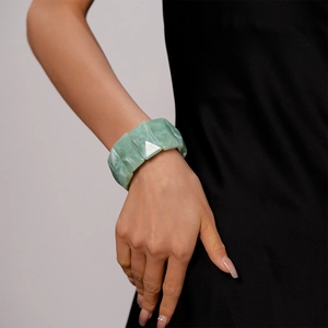 Close-up of green marble-textured resin wide geometric bracelet worn by a model