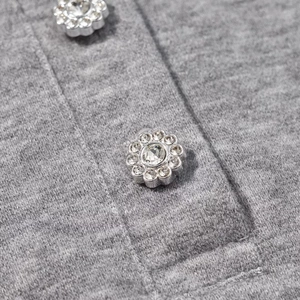 Close-up of floral silver buttons with crystals on grey knit polo set fabric