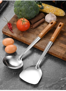 Macro view of stainless steel spatula and soup ladle with wooden handles on a cutting board