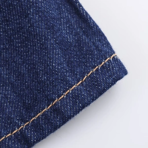 Détail macro des coutures contrastées et de la texture du denim bleu marine pour femmes