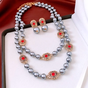 Macro shot of grey pearls and gold metal accents with red stones in a jewelry box