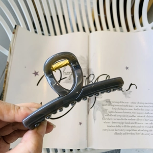 Gros plan d'une pince à cheveux gris foncé brillant avec ressort doré sur fond stylé