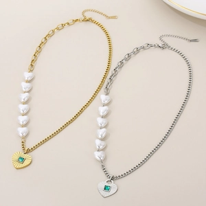Detailed shot of gold and silver necklaces with heart pearls and green stone pendants
