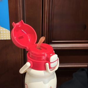 Close-up of the dual-purpose lid with a silicone straw spout on a red and white water bottle