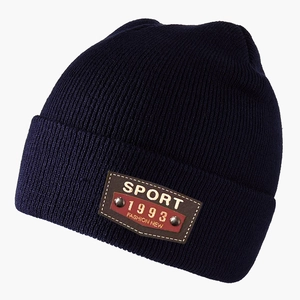 Detailed texture of dark blue ribbed knit beanie with leather sport brand label