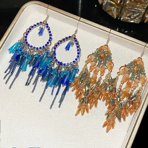 Detailed view of crystal tassel earrings in blue and champagne on a jewelry box