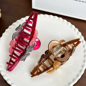 Large acetate flower hair claw clips with rhinestones on a decorative ceramic tray