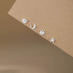 Macro shot of silver S925 earrings set with moon star sun and saturn stud designs