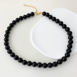 Macro shot of minimalist black onyx beaded necklace with elegant gold lobster clasp
