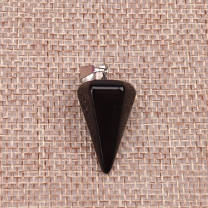 Detail view of a black faceted stone cone pendant on a natural woven linen background