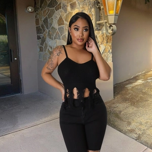 Women's black ribbed knit crop top featuring distressed fringe details in an outdoor setting