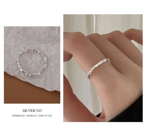 Macro detail of minimalist 925 sterling silver square bead ring on textured background