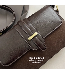 Detail of dark brown baguette bag featuring suede texture and gold buckle hardware