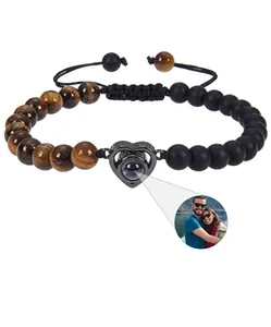 Close-up of heart charm on brown tiger eye bead bracelet with photo projection feature