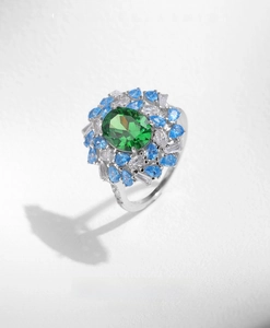 Detailed shot of an s925 silver ring featuring a large green emerald-cut stone and blue zircons