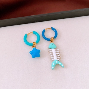 Detail of asymmetrical titanium earrings with blue starfish and fishbone charms