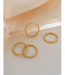 Macro view of four minimalist polished rose gold titanium steel rings on silk background