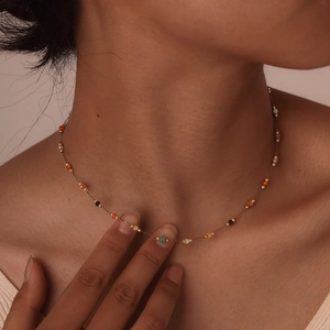 Detail of bohemian gold beaded necklace with colorful amber stones on a model's neck