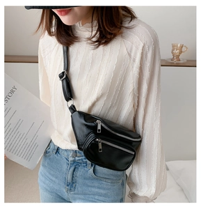 Detail of black PU leather waist bag with silver zippers worn by a fashion model
