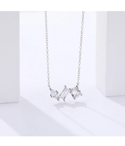 Detail view of a 925 silver necklace with three zircon stones on white geometric props