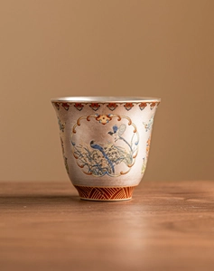 Macro detail of enamel kung fu teacup featuring vibrant bird and flower patterns