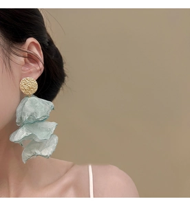 Detailed view of floral tassel earrings with golden hammered discs and green organza petals