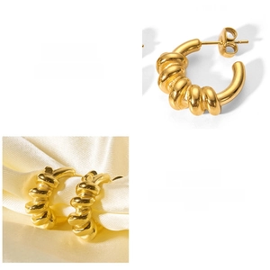 Macro view of C-shaped spring twisted earrings in 18k gold-plated stainless steel texture