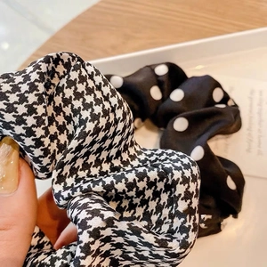 Close-up of silk scrunchies in black and white houndstooth and polka dot patterns