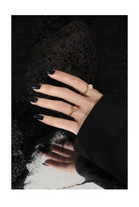 Detail of gold knot ring and white gemstone ring displayed on a dark mineral stone