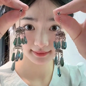 Detailed close-up of vintage tassel earrings with silver chains and teal teardrop pendants