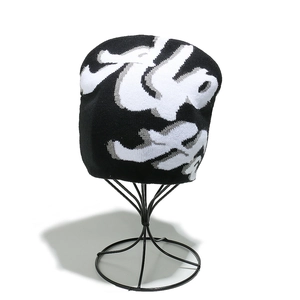 Detailed close-up showing high-density knitted fabric and graffiti jacquard pattern on a black beanie